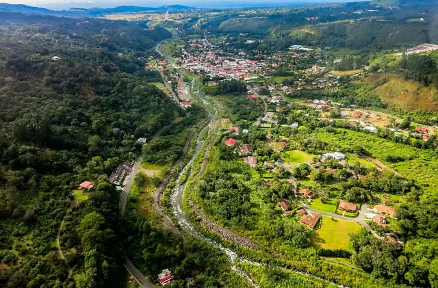 Vista aérea de Boquete entre montanhas verdes, com casas e um rio no vale.