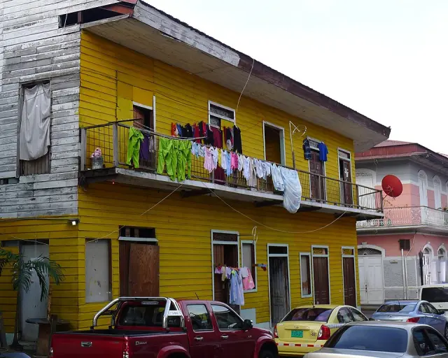 Um prédio amarelo com sacadas e roupas penduradas em uma rua do Casco Viejo.