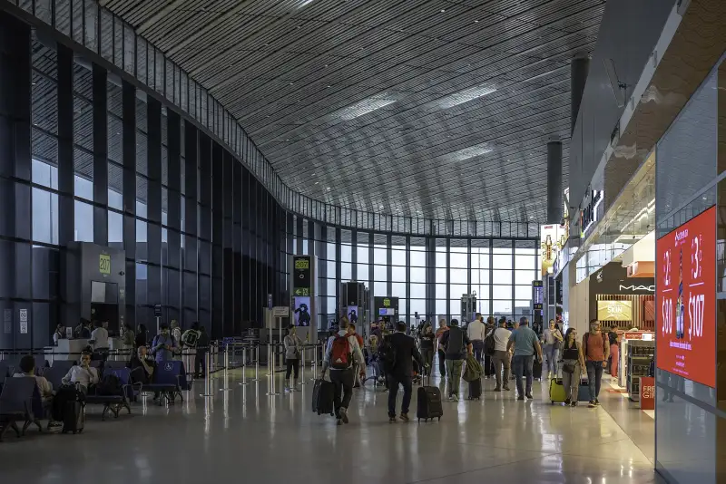 Passagiere in der weitläufigen Halle von Terminal 2 in Tocumen neben den hohen Fenstern.